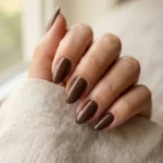 Almond nails painted in a glossy chocolate brown creme