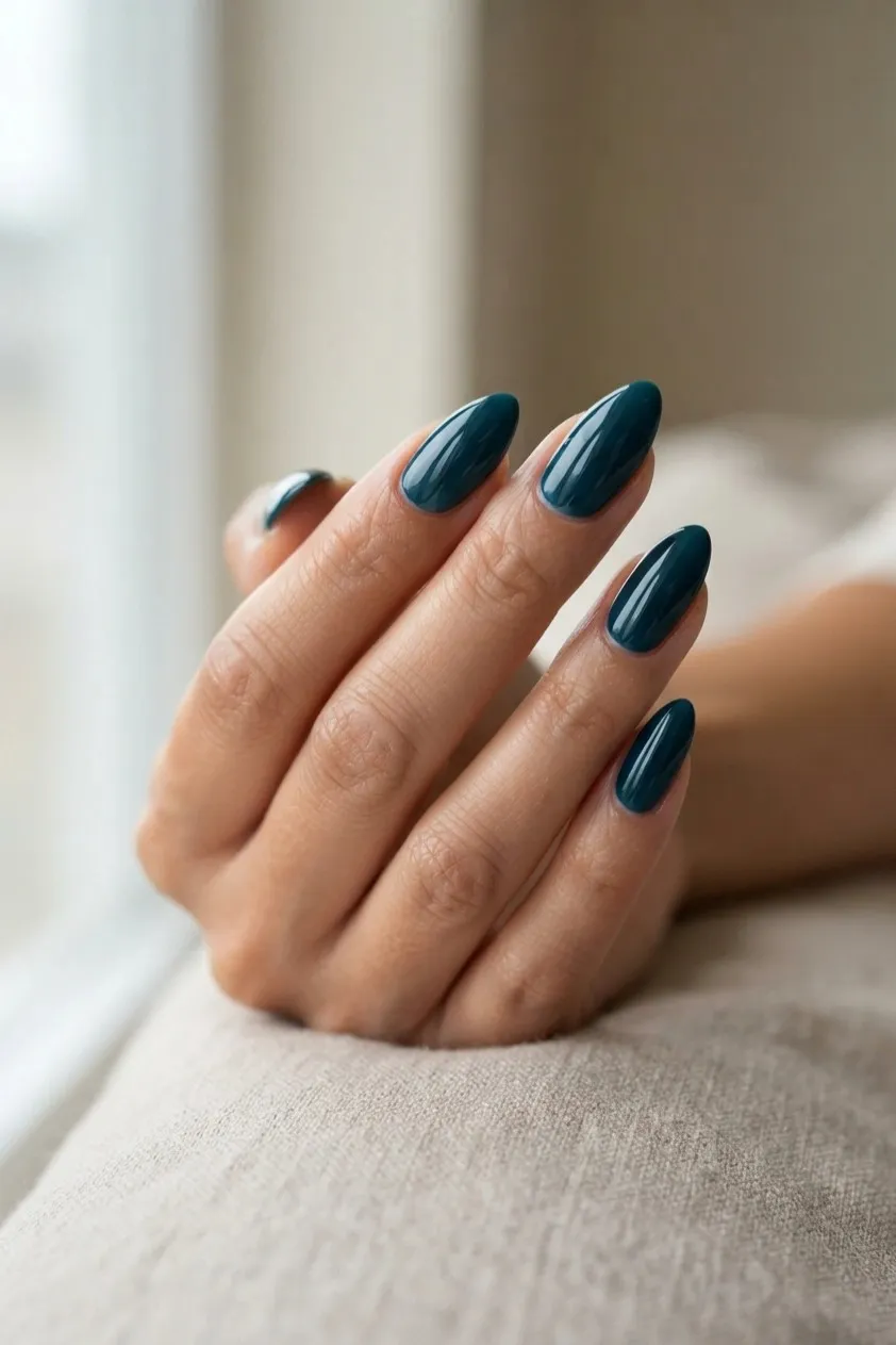 Almond nails in a glossy deep teal blue green
