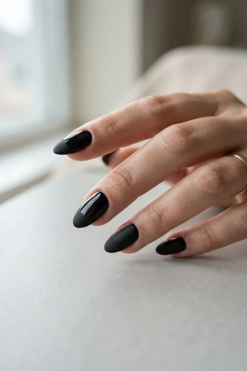 Glossy nude nails finished with a flat matte black tip for contrast