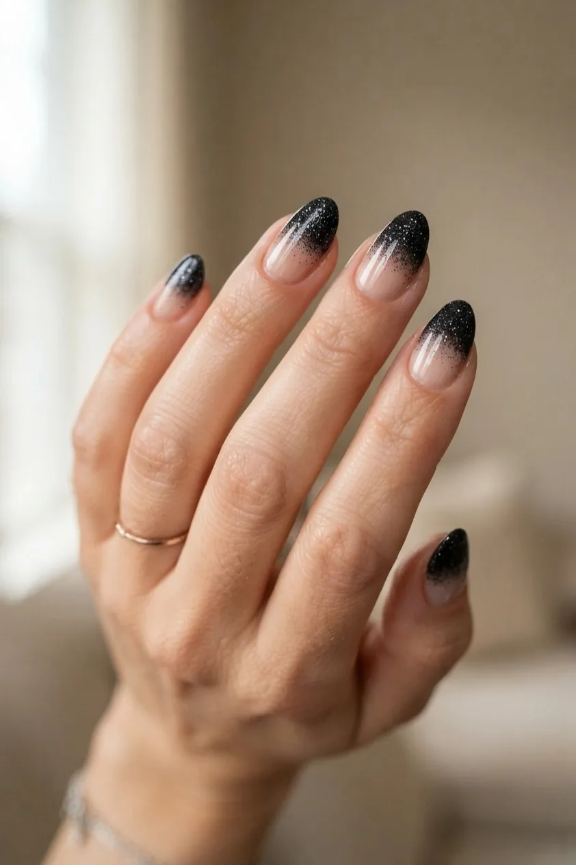 Nude nails with a black glitter gradient fading upward from the tip