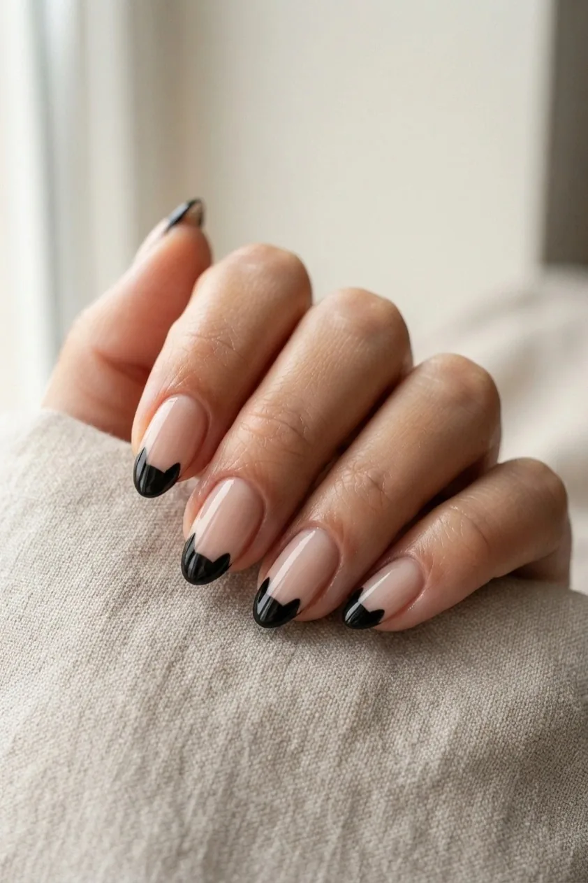 Nude nails with black cat ears shaped into the French tip line