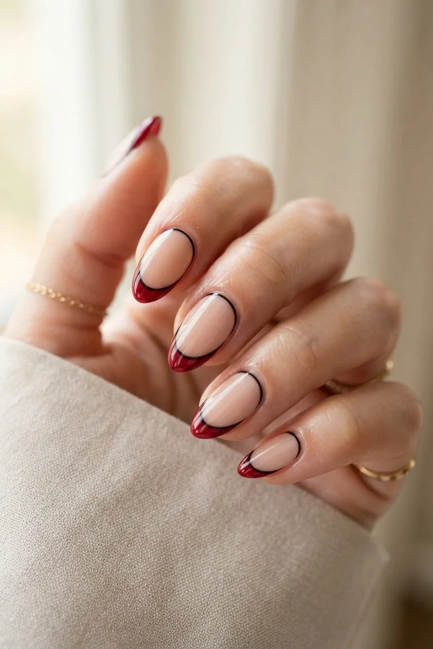 Nails with a deep red French tip outlined by a very fine black line