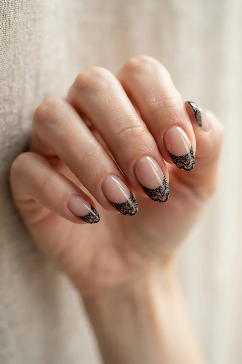 Nude nails with a delicate black lace pattern worked along the tip