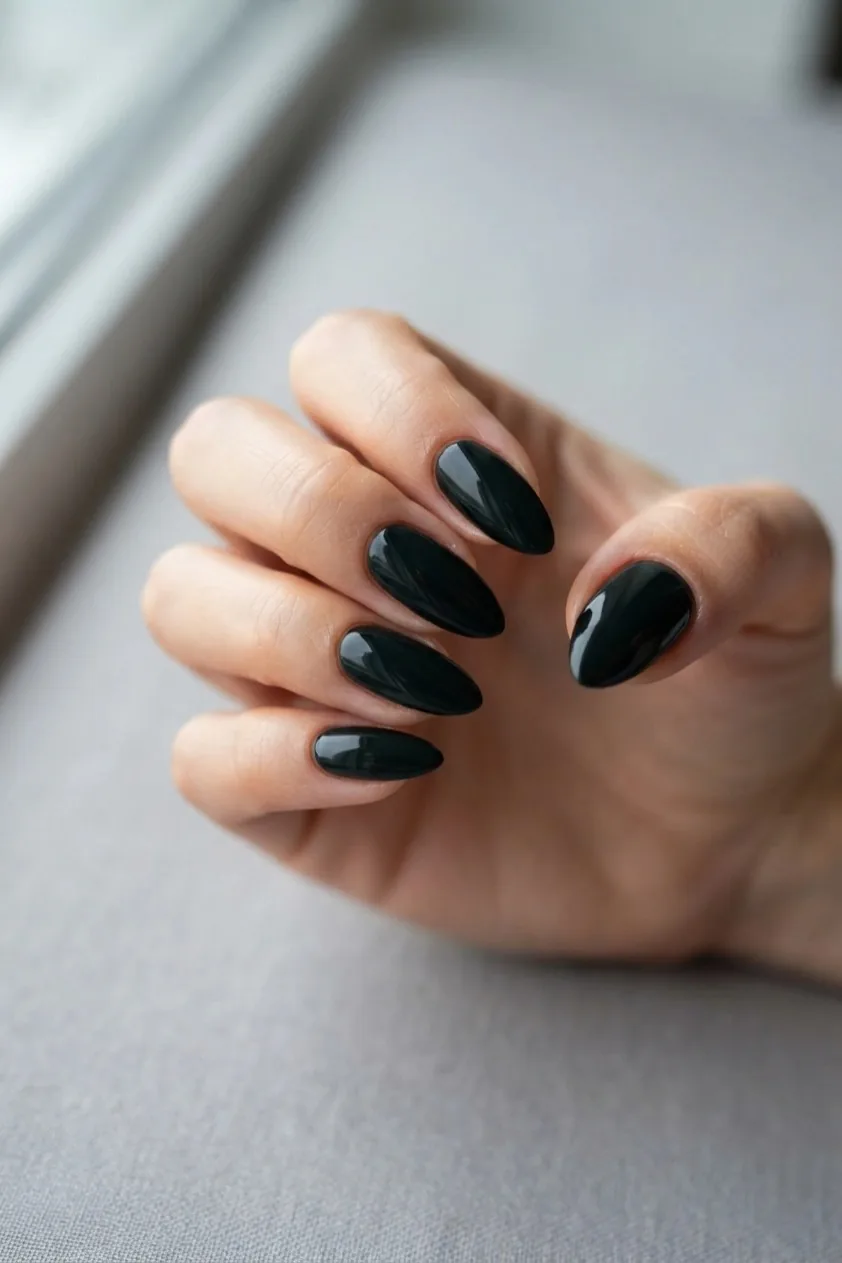 Almond nails in a very dark forest pine green that reads almost black