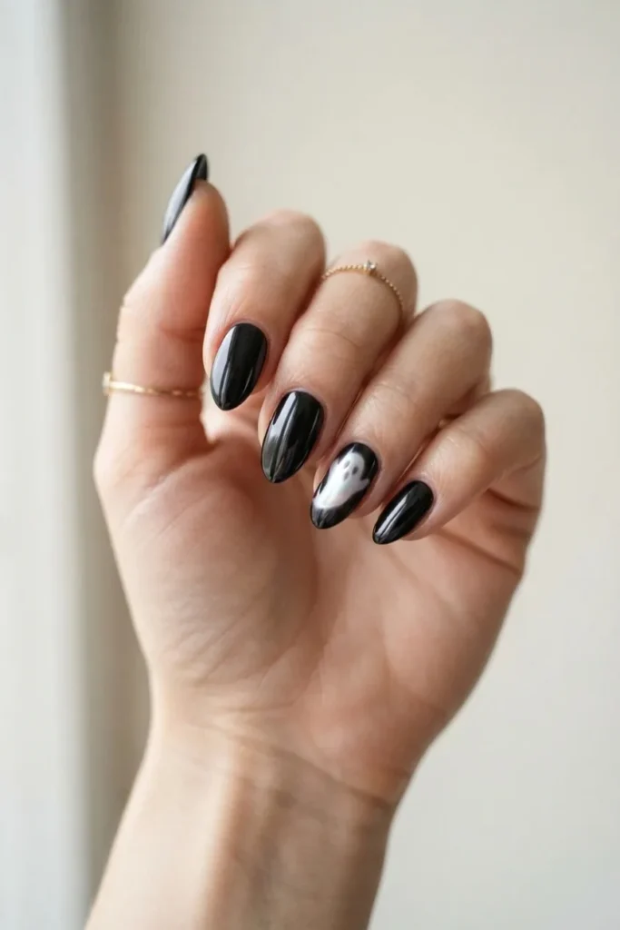 Black chrome nails with a pearl white ghost painted on the ring finger