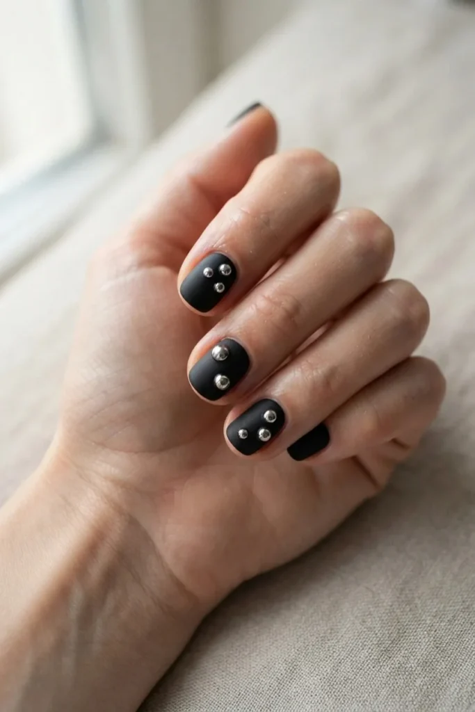 Matte black nails with raised silver chrome droplets like beads of mercury