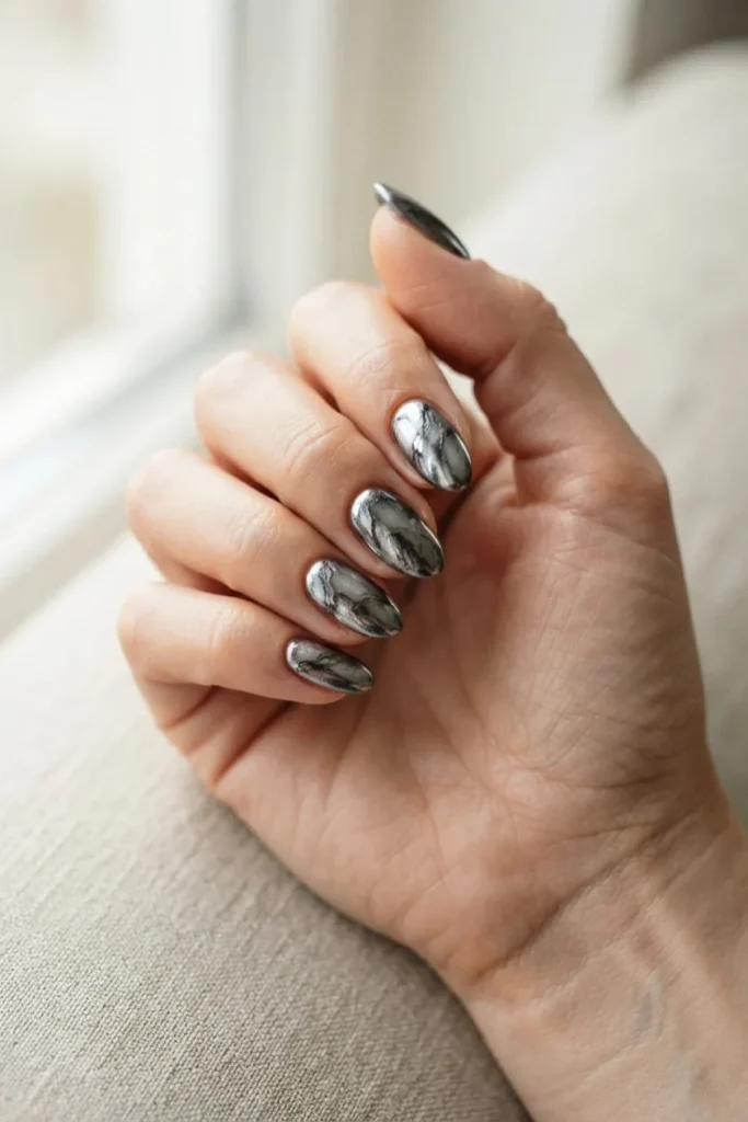 Short almond nails in a marbled mix of silver and gunmetal chrome
