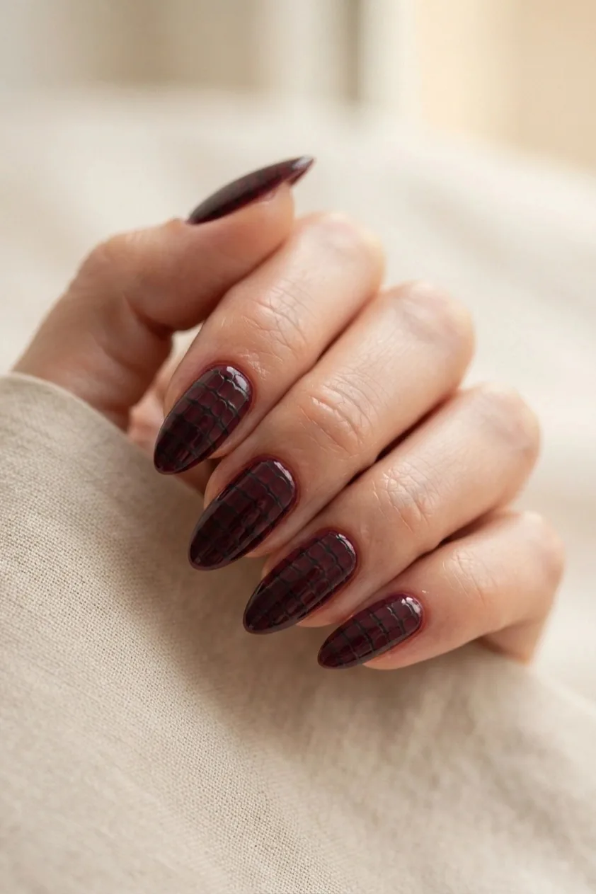 Burgundy French tip over a sheer nude base on almond nails