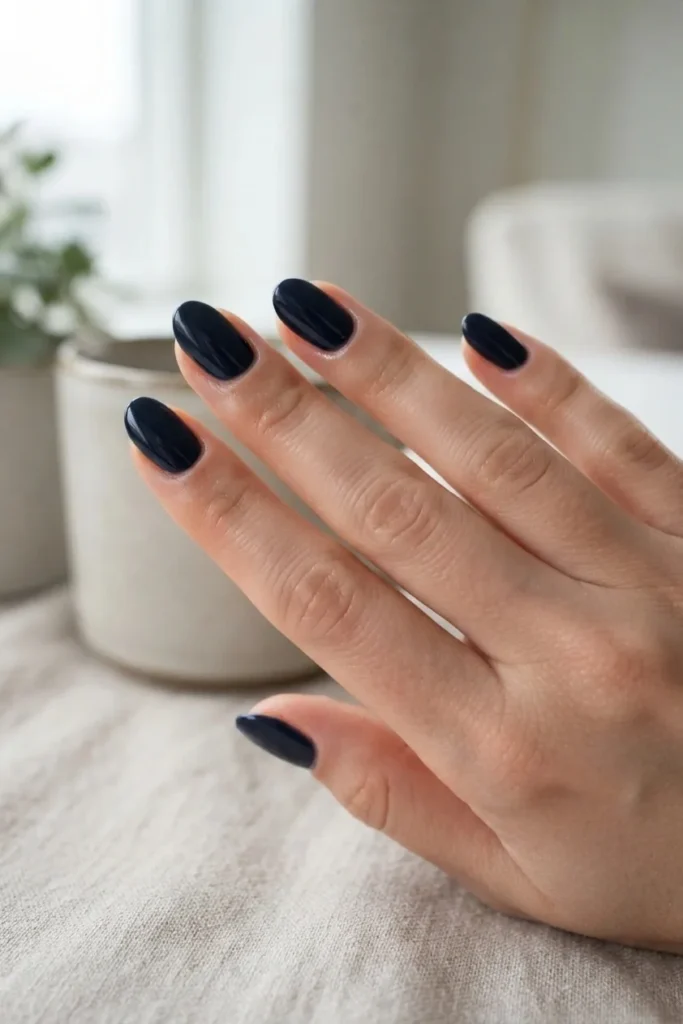 Short almond nails in a deep near-black navy blue creme polish