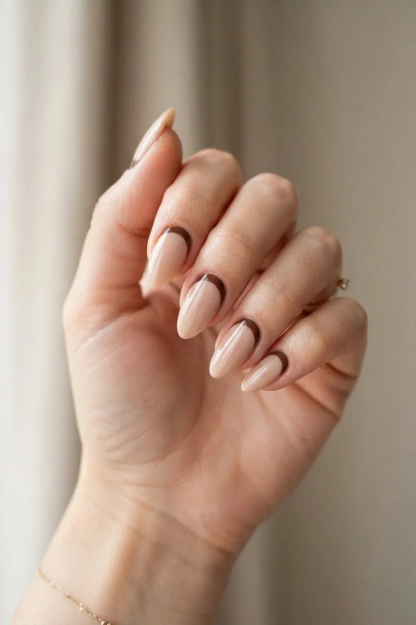 Reverse French manicure with a brown curve painted at the cuticle