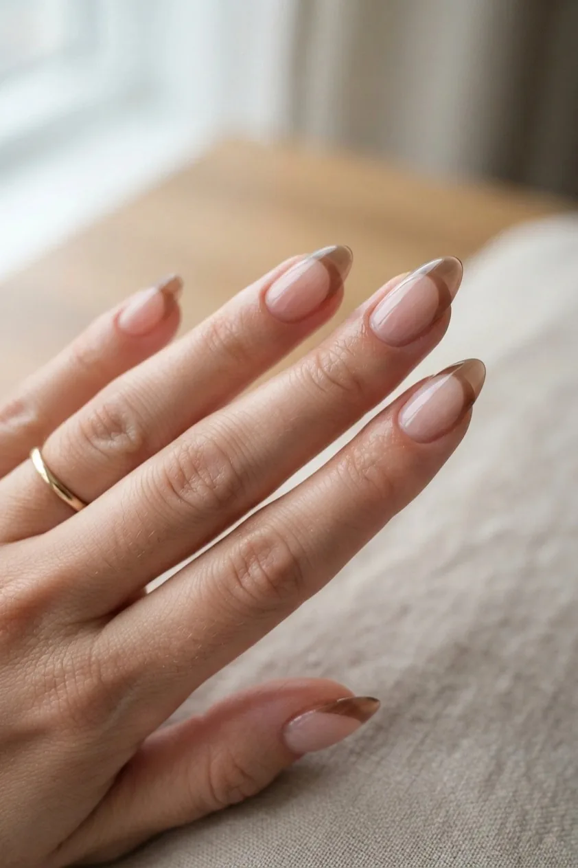 Wide sheer brown French tip on long almond nails